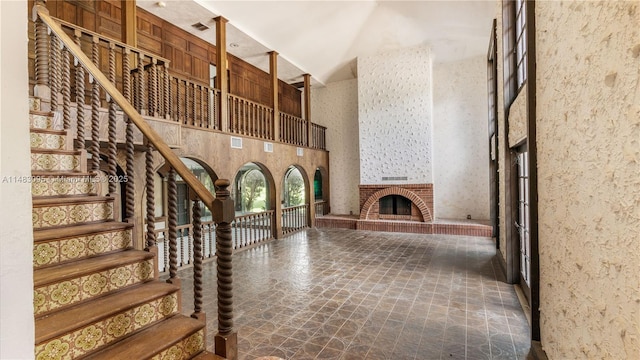 interior space with a towering ceiling, a brick fireplace, and stairs