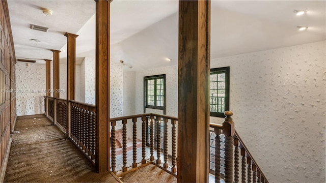 hall featuring wallpapered walls, an upstairs landing, visible vents, and ornate columns