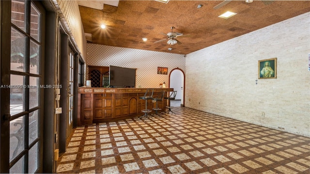 interior space featuring wallpapered walls, arched walkways, indoor bar, and a ceiling fan