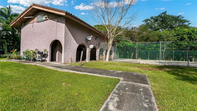 exterior space featuring a tile roof, a yard, fence, and stucco siding