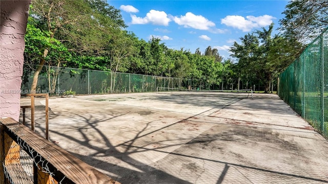 view of property's community with a tennis court and fence