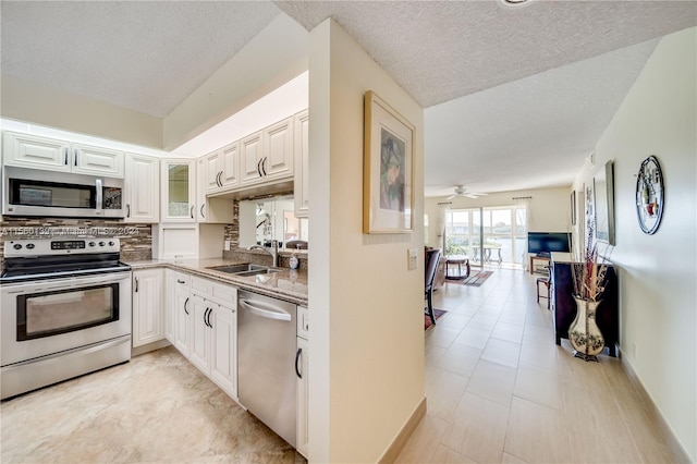 kitchen with ceiling fan, light tile floors, sink, appliances with stainless steel finishes, and white cabinetry