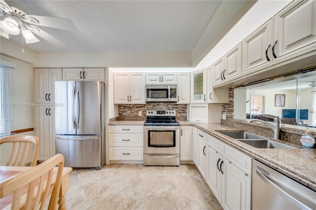 kitchen featuring ceiling fan, light tile floors, sink, appliances with stainless steel finishes, and white cabinetry