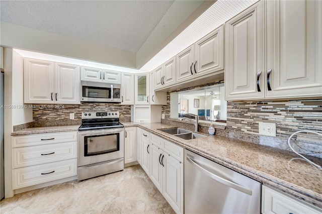 kitchen with light tile floors, appliances with stainless steel finishes, white cabinets, backsplash, and sink