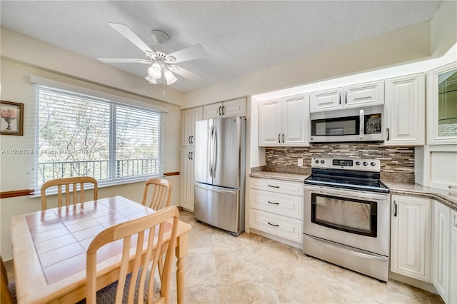 kitchen with ceiling fan, light tile floors, backsplash, stainless steel appliances, and white cabinetry