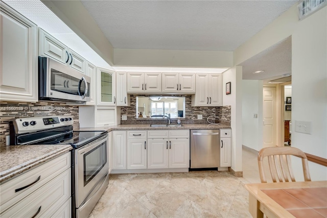 kitchen with light tile flooring, tasteful backsplash, stainless steel appliances, and white cabinets