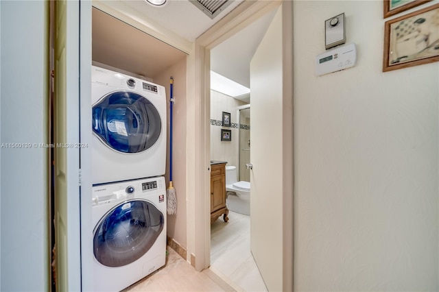 clothes washing area featuring light tile floors and stacked washer and dryer