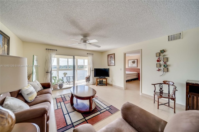 tiled living room with a water view, ceiling fan, and a textured ceiling