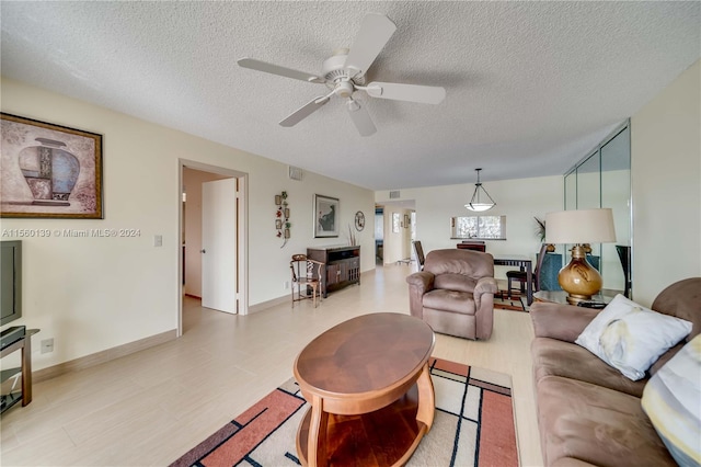 living room featuring ceiling fan and a textured ceiling