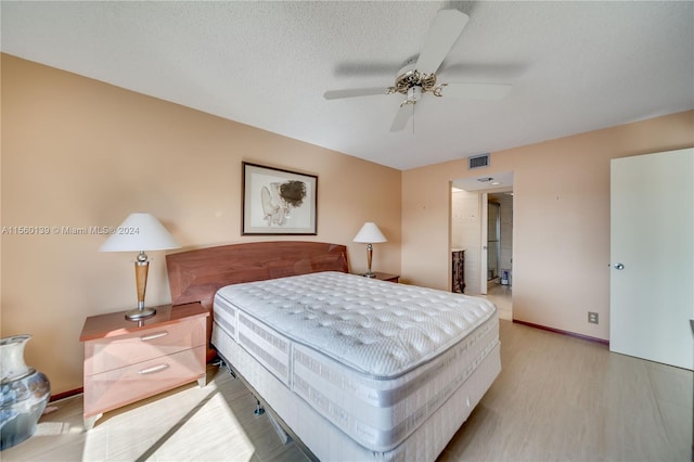 bedroom featuring light hardwood / wood-style floors, a textured ceiling, and ceiling fan