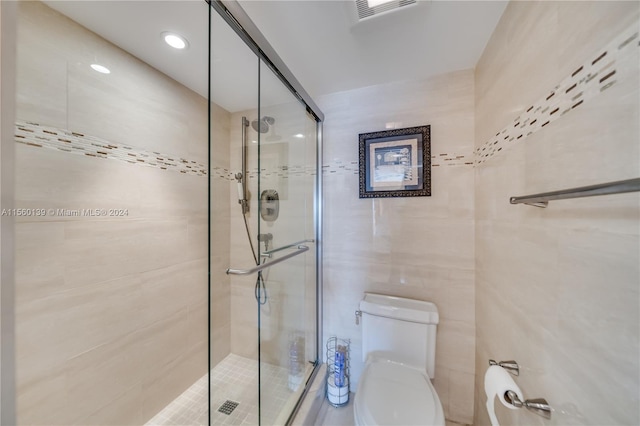 bathroom with toilet, an enclosed shower, and tile walls