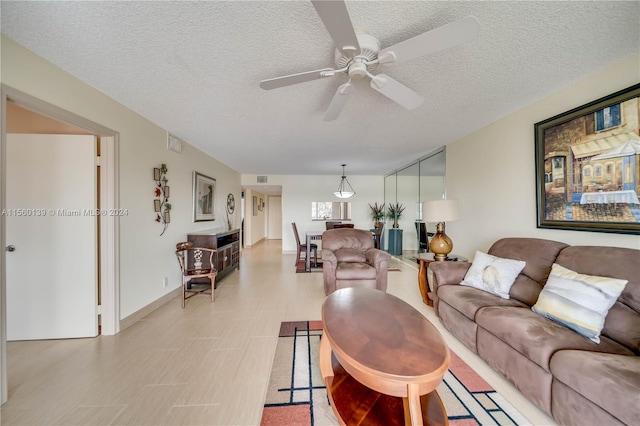 living room with ceiling fan and a textured ceiling