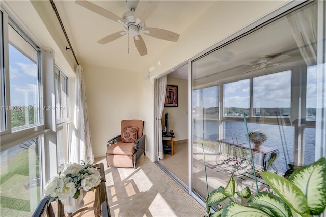 sunroom featuring a water view and ceiling fan