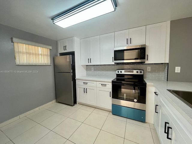 kitchen featuring stainless steel appliances, white cabinetry, light tile flooring, and backsplash