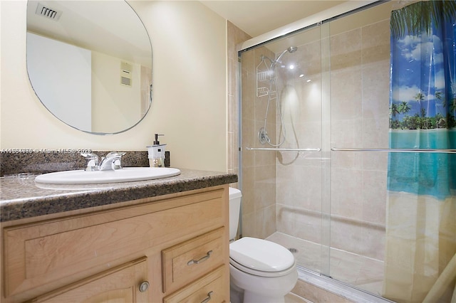 bathroom with a shower with shower door, vanity, and toilet