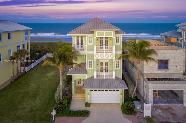 view of front of property with a balcony, a garage, a water view, and french doors