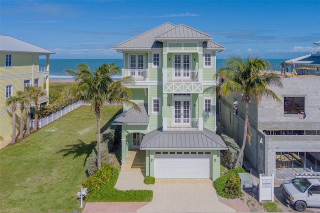 beach home featuring a water view, a garage, a porch, and french doors