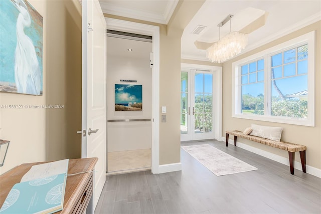 interior space featuring crown molding, a notable chandelier, french doors, and light hardwood / wood-style floors