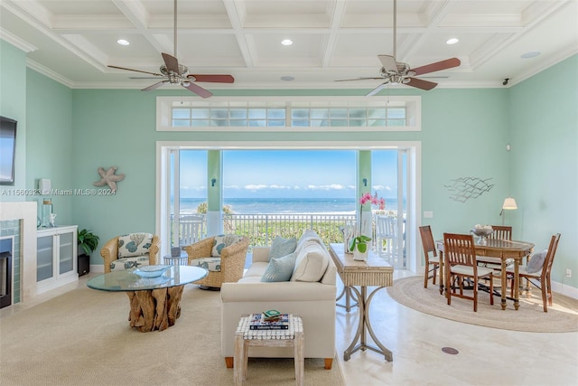 living room with a water view, coffered ceiling, ceiling fan, and a tile fireplace