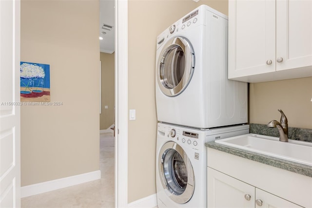 washroom with light tile patterned floors, cabinets, stacked washer and clothes dryer, and sink