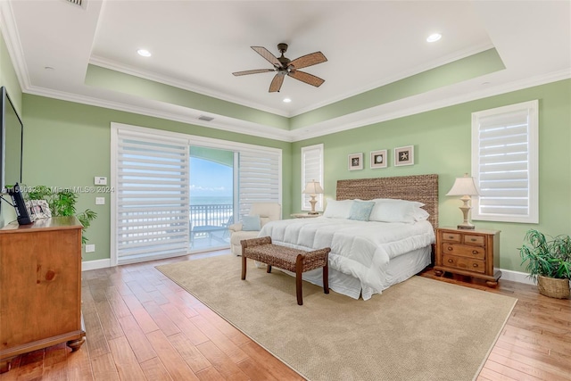 bedroom with light wood-type flooring, a tray ceiling, access to exterior, and ceiling fan