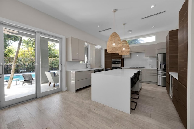 kitchen with decorative light fixtures, backsplash, appliances with stainless steel finishes, a kitchen bar, and a kitchen island