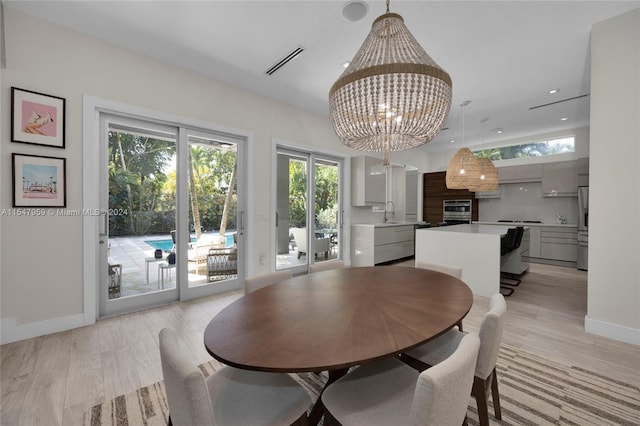 dining area featuring sink, light hardwood / wood-style flooring, french doors, and an inviting chandelier