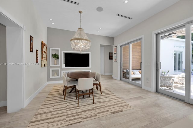 dining space featuring a healthy amount of sunlight, a notable chandelier, and light wood-type flooring