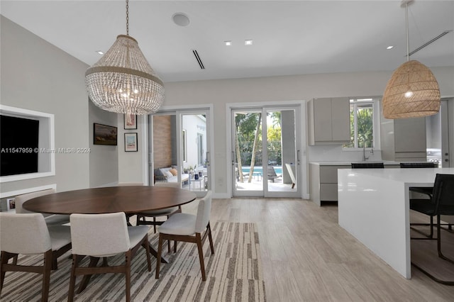 dining area with an inviting chandelier, lofted ceiling, and light wood-type flooring