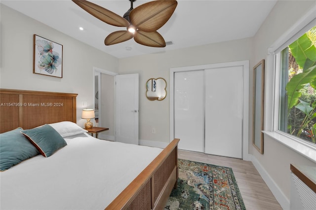 bedroom with a closet, ceiling fan, light hardwood / wood-style floors, and multiple windows