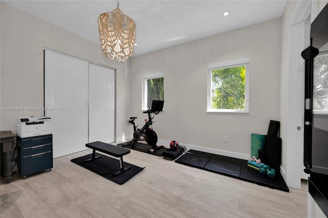 workout area featuring a notable chandelier and light hardwood / wood-style flooring