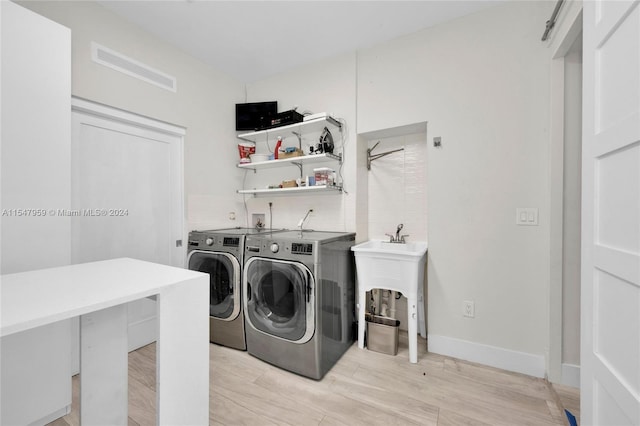 laundry room featuring hookup for a washing machine, light hardwood / wood-style floors, and washing machine and clothes dryer