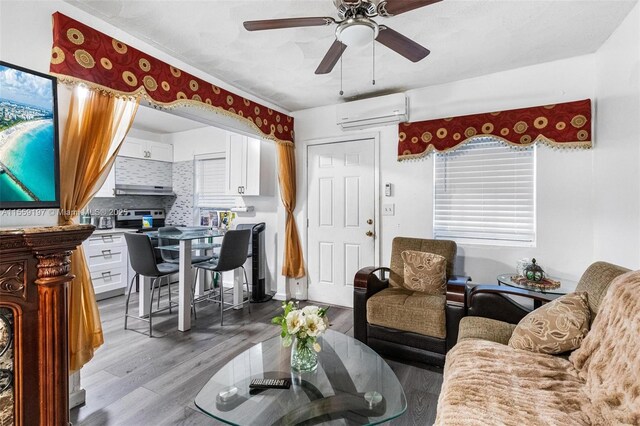 living room with light hardwood / wood-style flooring, a wall mounted air conditioner, and ceiling fan