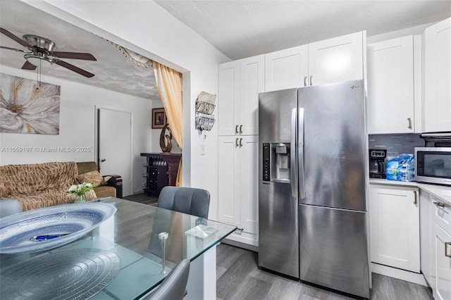 kitchen with decorative backsplash, appliances with stainless steel finishes, white cabinets, ceiling fan, and wood finished floors