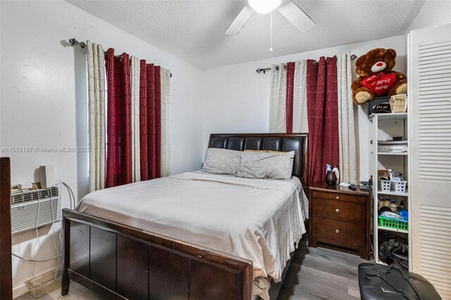 bedroom with dark wood-type flooring, ceiling fan, and a textured ceiling