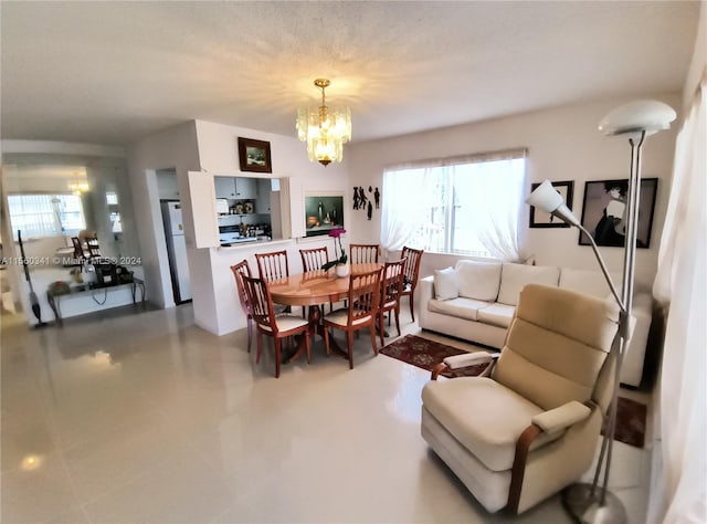 living room featuring plenty of natural light, tile floors, a textured ceiling, and an inviting chandelier