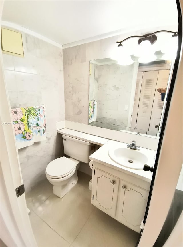 bathroom featuring tile floors, large vanity, toilet, and tile walls