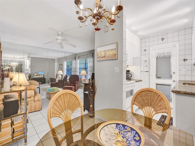 dining area featuring light tile patterned floors and ceiling fan with notable chandelier