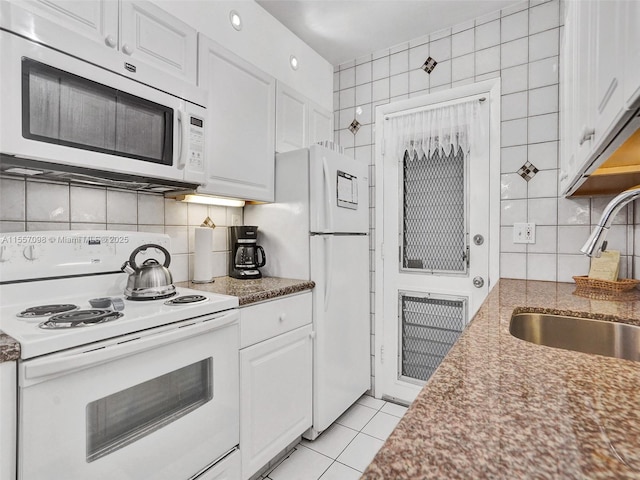 kitchen featuring light tile patterned floors, decorative backsplash, white cabinets, a sink, and white appliances