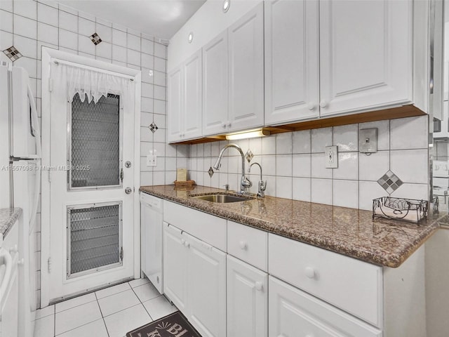 kitchen with white appliances, light tile patterned flooring, a sink, and white cabinets