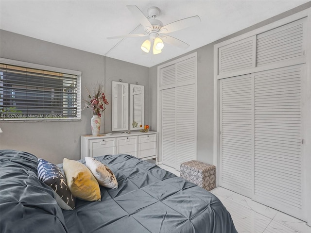 bedroom featuring ceiling fan, marble finish floor, and a closet