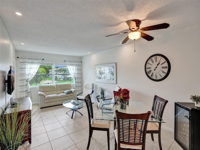 dining room featuring beverage cooler, a textured ceiling, ceiling fan, and light tile flooring