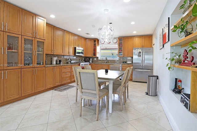 kitchen with appliances with stainless steel finishes, pendant lighting, decorative backsplash, sink, and a chandelier