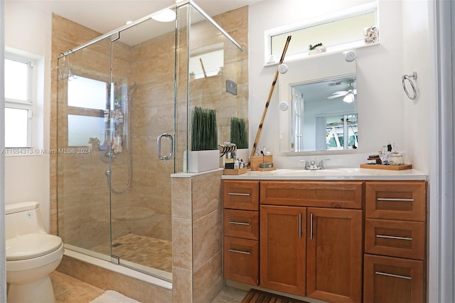 bathroom featuring tile patterned floors, toilet, vanity, ceiling fan, and a shower with shower door