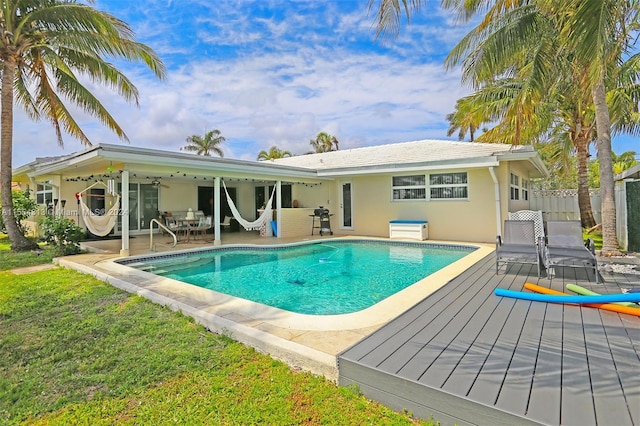 view of pool with grilling area, a patio area, a deck, ceiling fan, and a yard