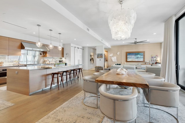 dining room featuring ceiling fan with notable chandelier, plenty of natural light, and light hardwood / wood-style floors