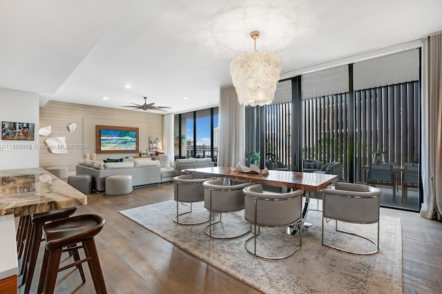 dining space featuring floor to ceiling windows, ceiling fan with notable chandelier, and hardwood / wood-style flooring