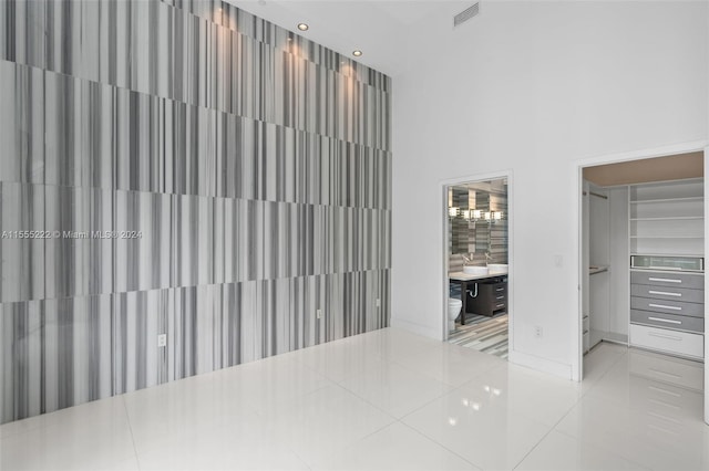 tiled empty room featuring a towering ceiling