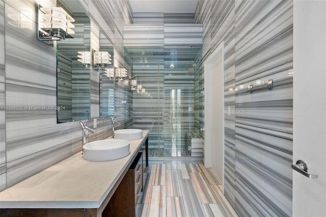 bathroom with tile walls, oversized vanity, double sink, and tile flooring