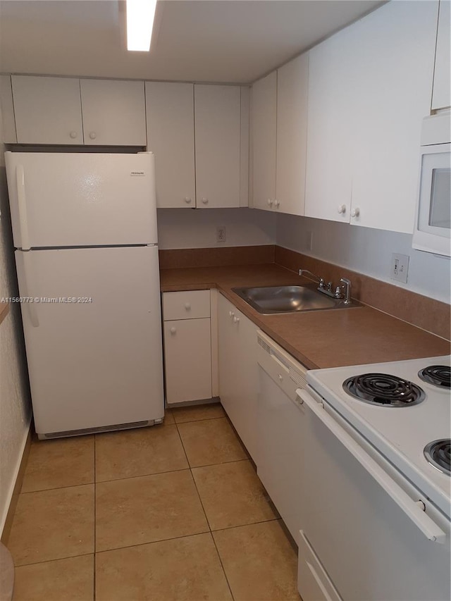 kitchen with white appliances, white cabinetry, light tile floors, and sink